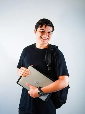 Integrante do time da Mamute, sorrindo, com notebook e mochila.