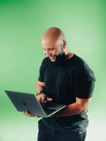 Integrante do time da Mamute, sorrindo, com um notebook nas mãos.