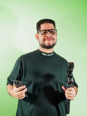 Integrante do time da Mamute, de óculos, com celular e estabilizador de câmera.