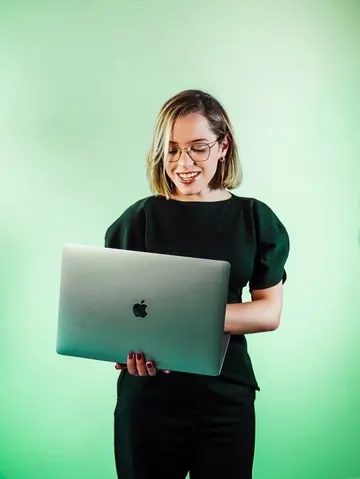 Integrante do time da Mamute, de óculos, com um notebook, em fundo verde.